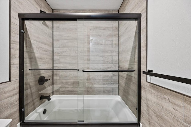 bathroom with bath / shower combo with glass door