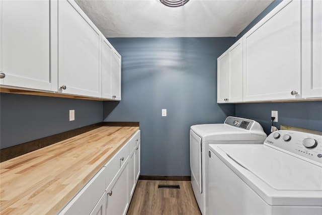 clothes washing area with baseboards, cabinet space, wood finished floors, and washing machine and clothes dryer