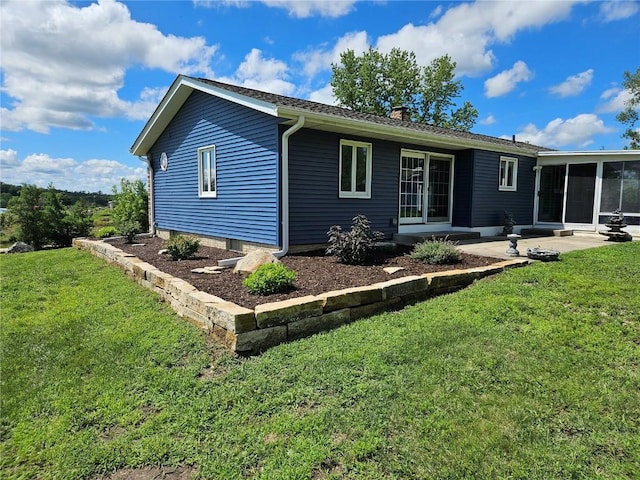 rear view of property featuring a lawn, entry steps, a chimney, and a sunroom