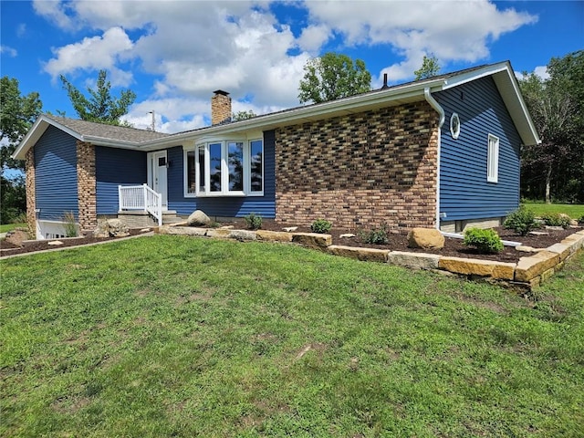 ranch-style house with a chimney, a front yard, and brick siding