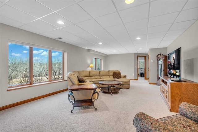 living room featuring a paneled ceiling, baseboards, and light colored carpet