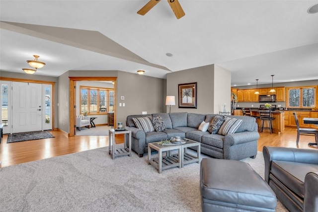 living area featuring light wood finished floors, baseboards, a ceiling fan, and vaulted ceiling