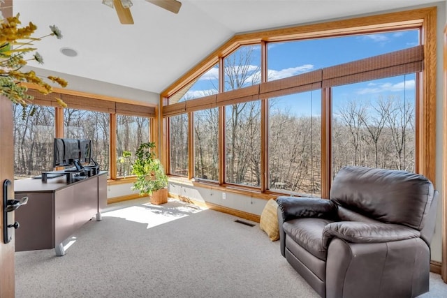 sunroom / solarium with visible vents, ceiling fan, a wooded view, and lofted ceiling