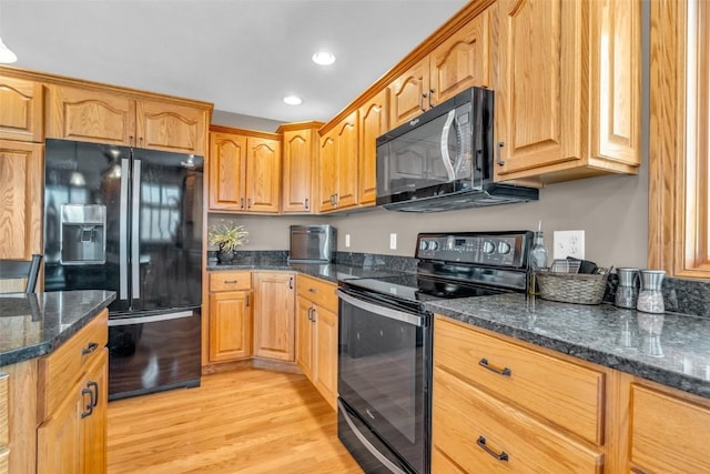 kitchen featuring dark stone countertops, brown cabinets, recessed lighting, black appliances, and light wood-type flooring