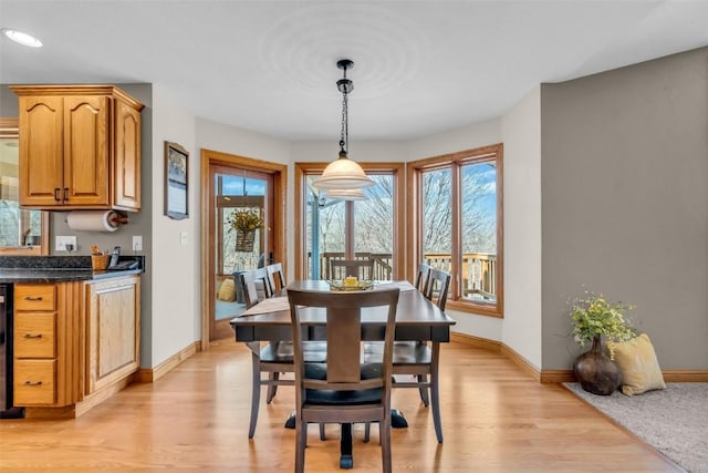 dining area featuring wine cooler, light wood-style flooring, and baseboards