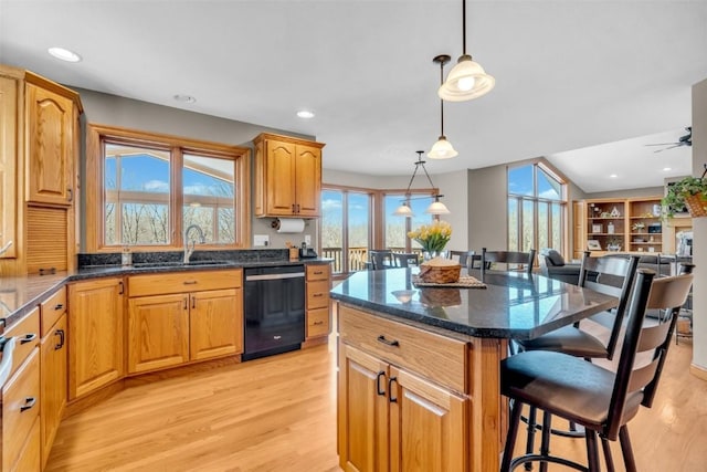 kitchen with a kitchen bar, light wood-type flooring, a sink, open floor plan, and dishwasher