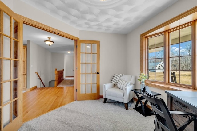 living area featuring an upstairs landing, french doors, baseboards, and carpet floors