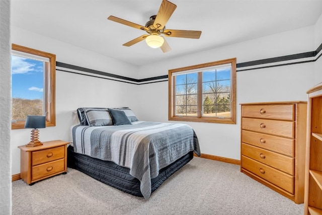 bedroom featuring baseboards, light colored carpet, and ceiling fan