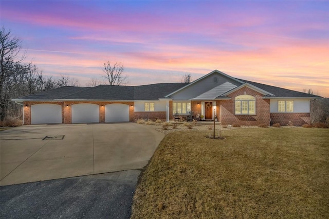 ranch-style house with a yard, brick siding, a garage, and driveway