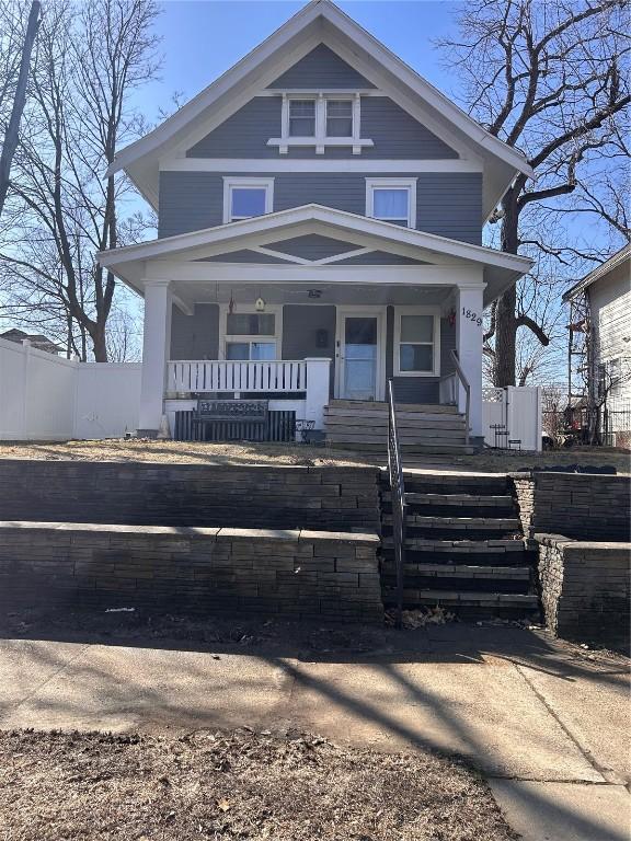 american foursquare style home with a porch and fence