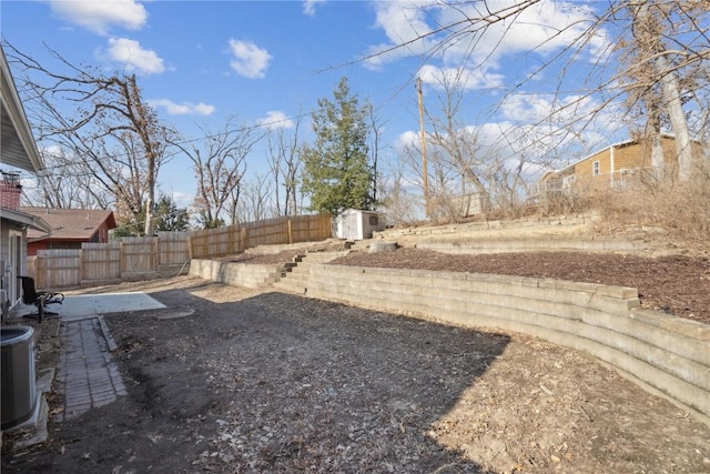 view of yard featuring an outbuilding, central air condition unit, a storage unit, and a fenced backyard