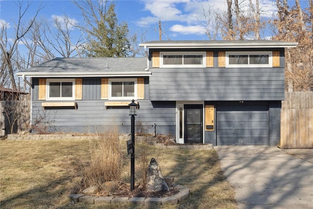 tri-level home featuring a garage, roof with shingles, concrete driveway, and fence