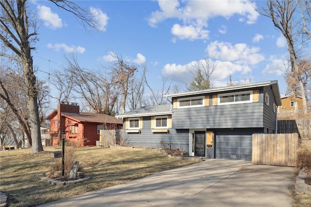 tri-level home featuring a garage, driveway, and fence