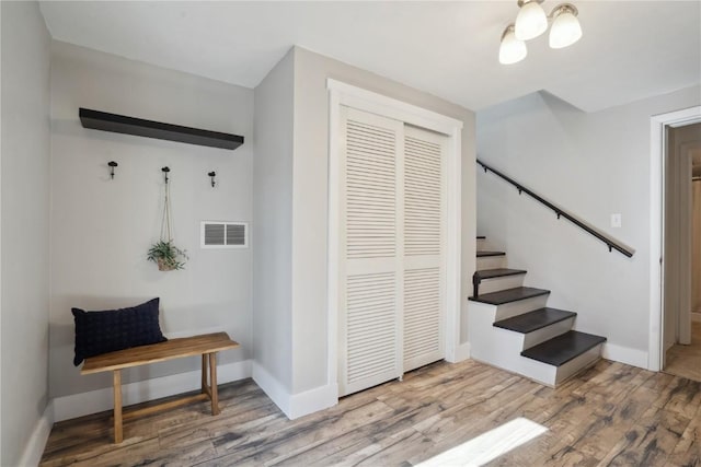 stairs featuring wood finished floors, visible vents, and baseboards