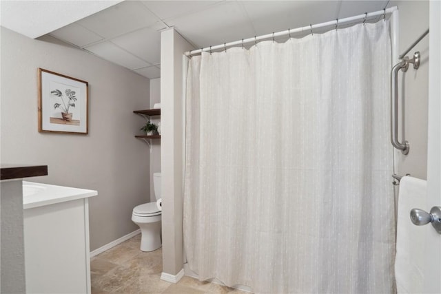 full bathroom featuring curtained shower, baseboards, a drop ceiling, toilet, and vanity