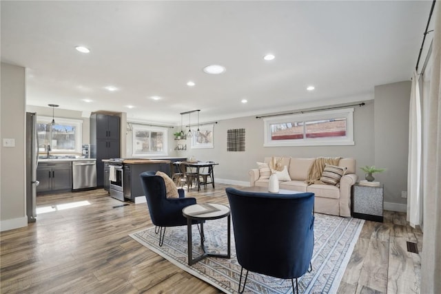 living area with recessed lighting, light wood-type flooring, and baseboards