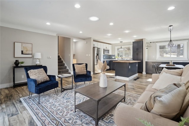 living room with stairway, recessed lighting, light wood-type flooring, and baseboards