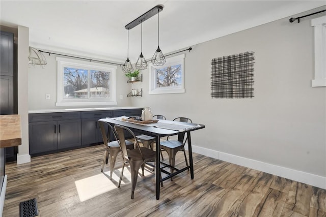 dining area with visible vents, baseboards, light wood-style floors, and an inviting chandelier