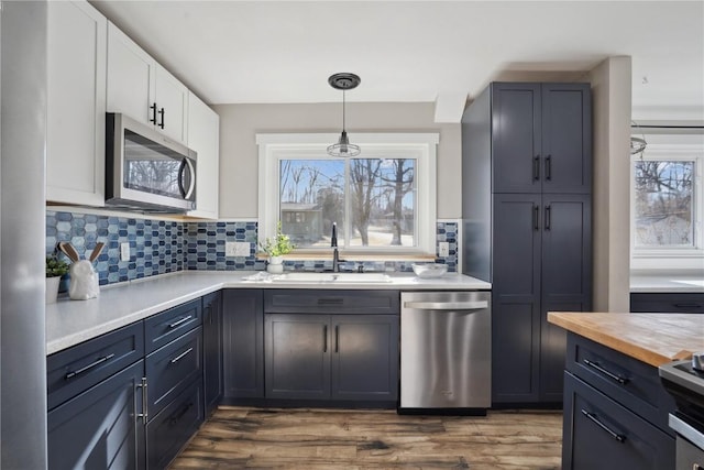 kitchen featuring a sink, plenty of natural light, appliances with stainless steel finishes, white cabinets, and wooden counters