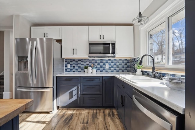 kitchen with a sink, tasteful backsplash, white cabinetry, stainless steel appliances, and light countertops