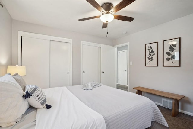 carpeted bedroom featuring visible vents, baseboards, two closets, and a ceiling fan