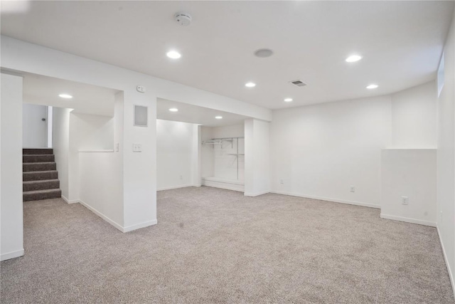 finished basement featuring visible vents, baseboards, light colored carpet, stairs, and recessed lighting