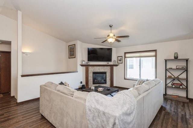 living area featuring a tile fireplace, baseboards, dark wood-style flooring, and ceiling fan