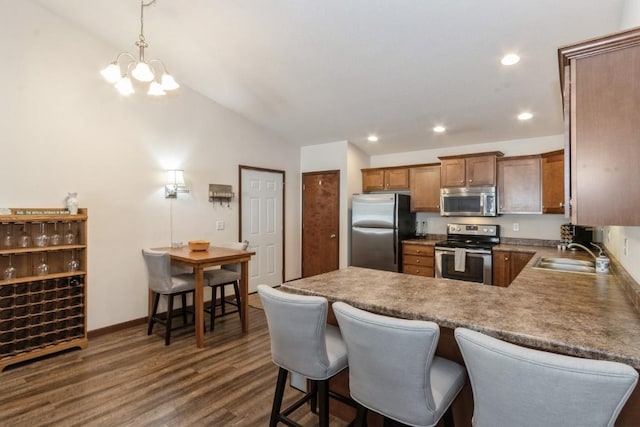 kitchen featuring brown cabinetry, lofted ceiling, dark wood-style flooring, a sink, and stainless steel appliances