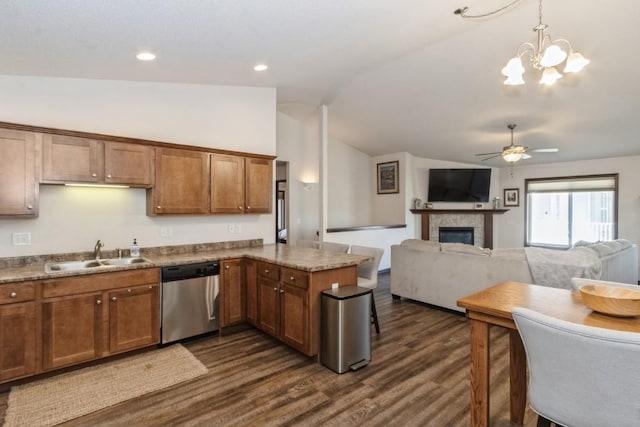 kitchen featuring dark wood-type flooring, lofted ceiling, a peninsula, stainless steel dishwasher, and a sink