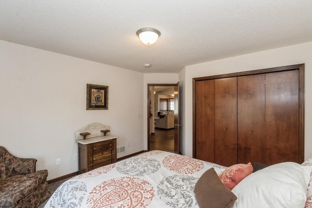 bedroom with a closet, visible vents, a textured ceiling, and baseboards