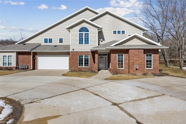 view of front of property with brick siding, an attached garage, driveway, and roof with shingles