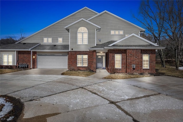 view of front of home with concrete driveway, an attached garage, and brick siding