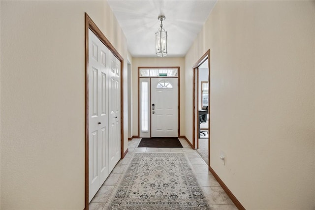 entrance foyer with light tile patterned floors, an inviting chandelier, and baseboards