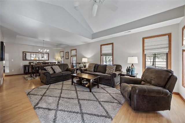 living room with light wood finished floors, lofted ceiling, a healthy amount of sunlight, and ceiling fan with notable chandelier