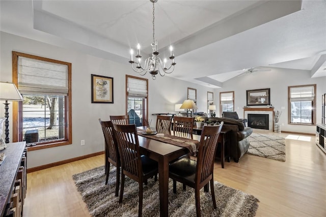 dining room featuring a raised ceiling, plenty of natural light, baseboards, and light wood-type flooring