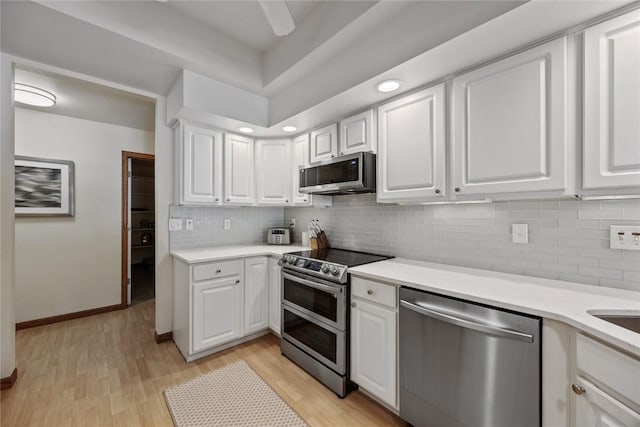 kitchen featuring decorative backsplash, white cabinetry, stainless steel appliances, and light countertops