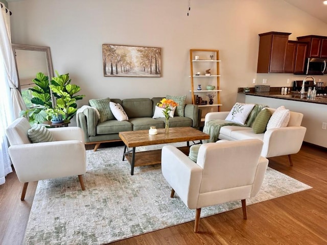 living area with high vaulted ceiling and wood finished floors