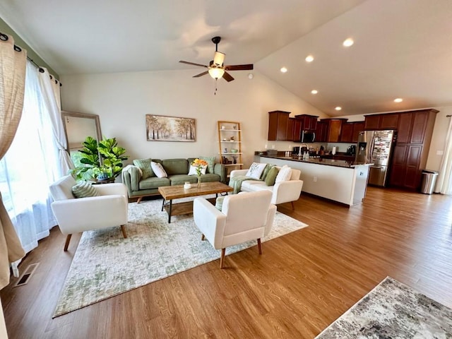 living area with a ceiling fan, vaulted ceiling, wood finished floors, and visible vents