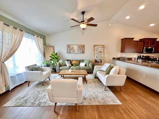 living area with wood finished floors, a ceiling fan, visible vents, recessed lighting, and vaulted ceiling