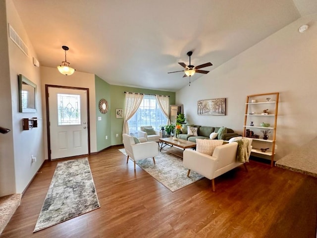 living area featuring dark wood-type flooring, a ceiling fan, visible vents, and vaulted ceiling