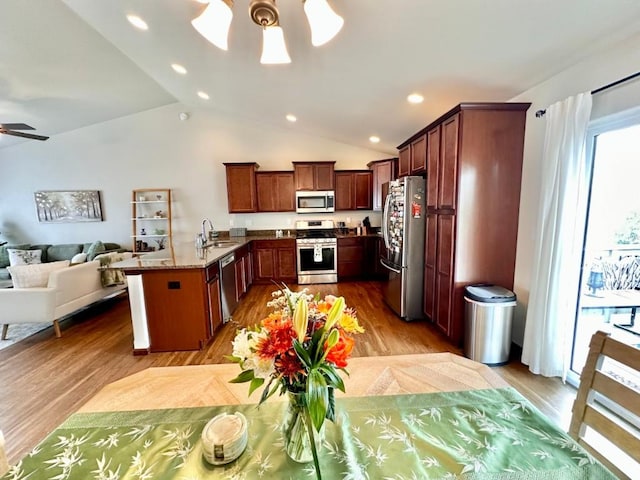 kitchen featuring light wood finished floors, ceiling fan, a sink, stainless steel appliances, and open floor plan