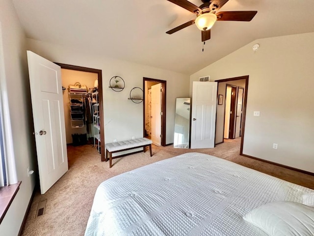 bedroom with a spacious closet, visible vents, lofted ceiling, light carpet, and a ceiling fan