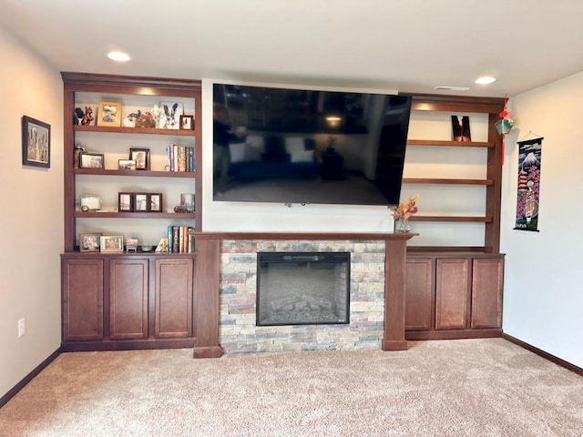 unfurnished living room with baseboards, carpet, and a stone fireplace