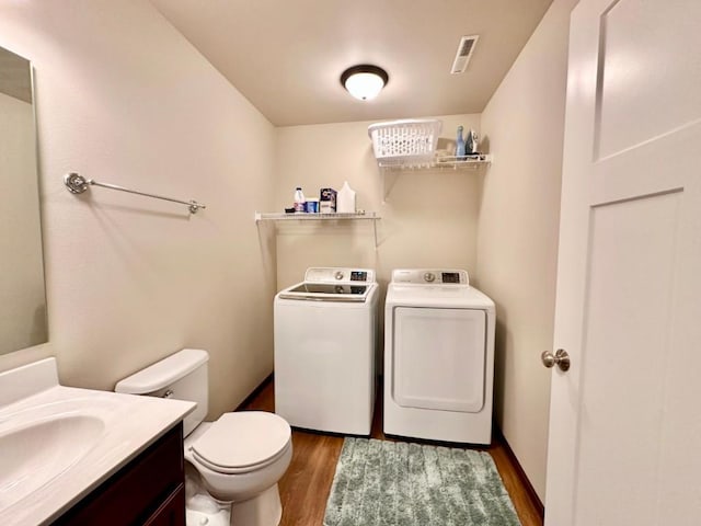 bathroom with vanity, wood finished floors, visible vents, separate washer and dryer, and toilet