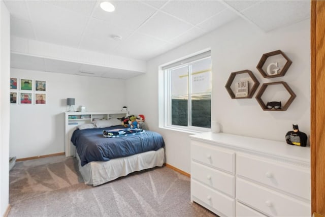 carpeted bedroom featuring baseboards and a drop ceiling