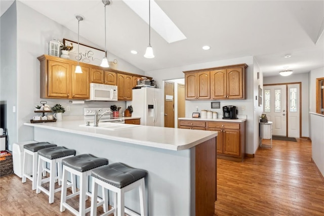 kitchen with white appliances, a breakfast bar, a peninsula, and light countertops