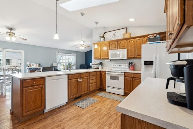 kitchen with white appliances, a peninsula, a sink, ceiling fan, and brown cabinets