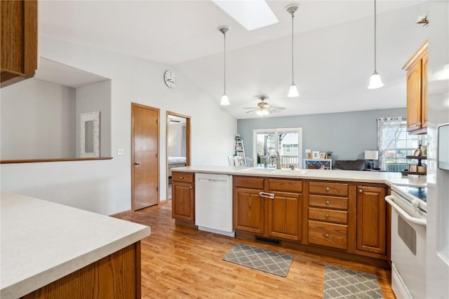 kitchen featuring a wealth of natural light, brown cabinets, white appliances, and a sink