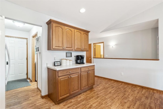 kitchen with baseboards, light countertops, recessed lighting, light wood-style floors, and brown cabinetry