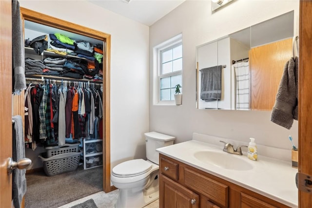 bathroom featuring toilet, vanity, and a walk in closet